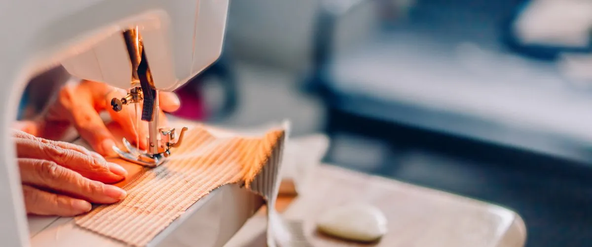 Close-up of hands sewing fabric with needle and thread